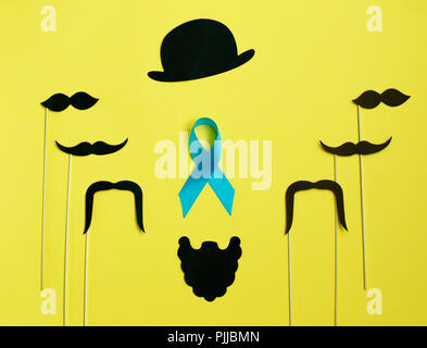 image of a man on paper. Beard and mustache blue ribbon. on yellow background. Concept of prostate cancer Stock Photo