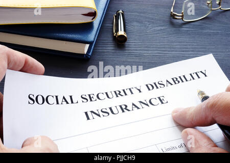 Man is holding Social Security Disability Insurance SSDI policy. Stock Photo
