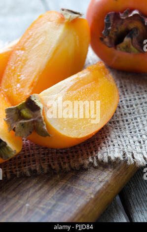Delicious fresh persimmon fruit on wooden cutting board. Stock Photo
