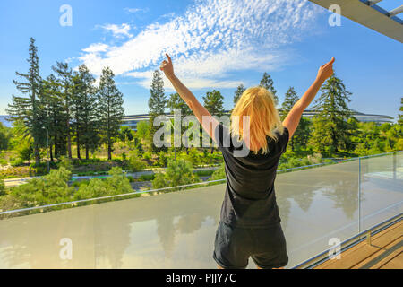 Cupertino, CA, United States - August 12, 2018: tourist woman enjoy the view of Apple Park with futuristic Campus from Roof Terrace of Apple Park Visitor Center in Silicon Valley, California. Stock Photo