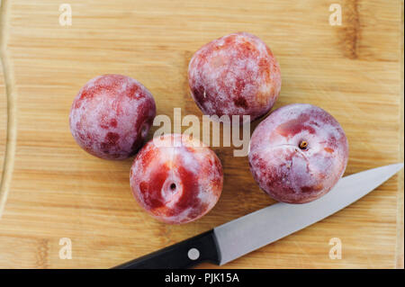 Top view of 4 honey punch pluots and knife on a wood cutting board Stock Photo