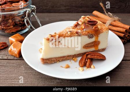 Slice of pecan caramel cheesecake on plate with a rustic wood background Stock Photo