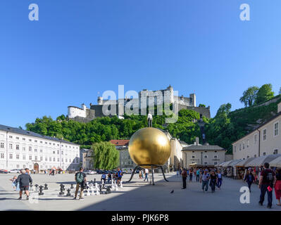 Salzburg, square Kapitelplatz, Hohensalzburg Castle, Sphaera, a sculpture of a man on a golden sphere in Austria, Salzburg, Stock Photo