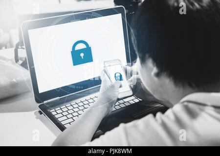 Network and internet devices security system. a man using mobile phone and computer laptop with lock icon technology on screen Stock Photo