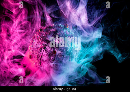 Silver shiny decoration Christmas balls in colored purple-red smoke, on an isolated black background. Concept of a modern Christmas card. Disco-ball i Stock Photo