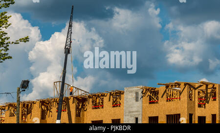 Construction workers on roof with crane and cumulus clouds in background Stock Photo