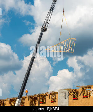 Construction workers on roof with crane and cumulus clouds in background Stock Photo