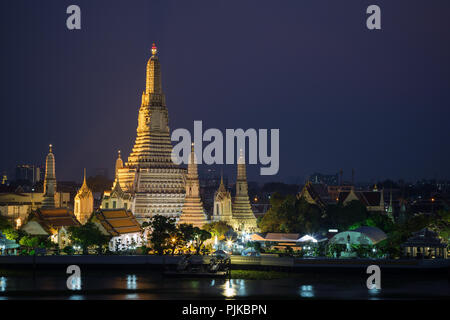 Beautiful view of lit Wat Arun temple next to Chao Phraya River in Bangkok, Thailand, in the evening. Stock Photo