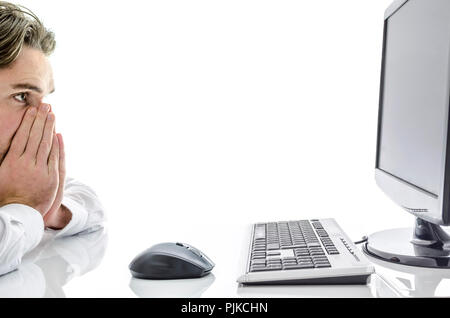 Worried man sitting at office desk, looking at computer monitor. Stock Photo