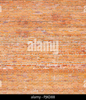 Large wall of red brick with a border of green grass Stock Photo