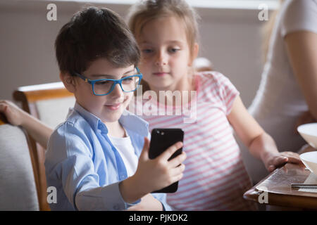Small boy showing video on smartphone to sister Stock Photo