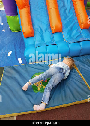 little Caucasian girl with blond hair in a denim suit playing in the Park. Stock Photo