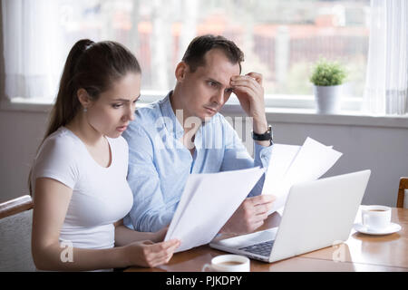 Worried husband and wife reading documents managing house paperw Stock Photo