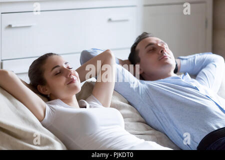 Man and woman lying on sofa relaxing with eyes closed Stock Photo
