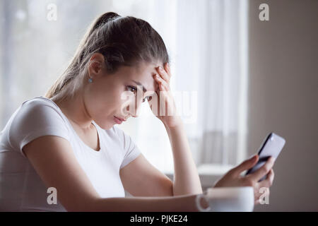 Upset young woman disappointed getting bad message on smartphone Stock Photo