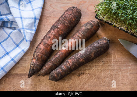three carrots on cutting board Stock Photo