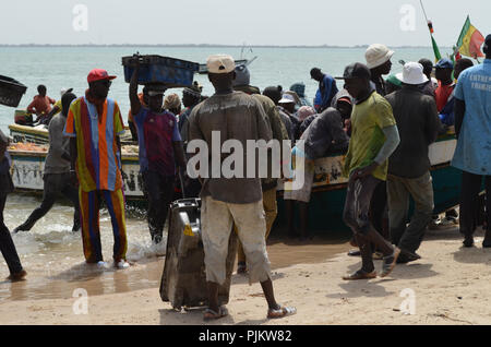A crowded beach in Mbour, Senegal, with fishers landing their catch and fishmongers selling the fish amidst concerns on the status of fish stocks Stock Photo
