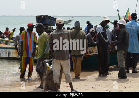 A crowded beach in Mbour, Senegal, with fishers landing their catch and fishmongers selling the fish amidst concerns on the status of fish stocks Stock Photo