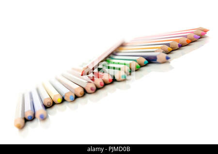 Red pencils lying on top of whole spectrum of other colored pencils. Isolated over white background. Stock Photo
