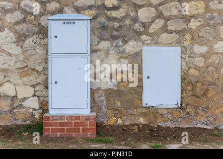 Electric boxes next to a stone wall Stock Photo