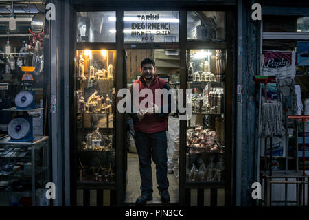 ISTANBUL, TURKEY - DECEMBER 29, 2015: Turkish salesman sanding in front of his souvenir shop selling copper metal crafts, mainly pepper grinders and c Stock Photo