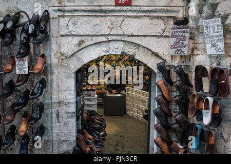 ISTANBUL, TURKEY - DECEMBER 28, 2015: Turkish salesman resting and checking his smartphone in his shop, selling shoes and boots, in the Beyazit distri Stock Photo