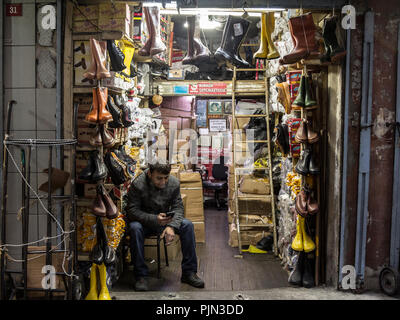 ISTANBUL, TURKEY - DECEMBER 29, 2015: Turkish salesman smoking cigarettes in front of his shop, selling shoes and boots, near the Spice bazaar, on the Stock Photo