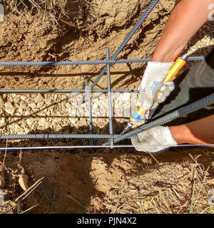 workers hands using steel wire and pincers to secure rebar before concrete is poured over it 2018 Stock Photo