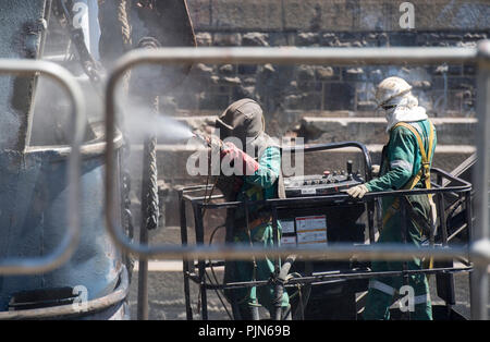 Shipyard employees working on a large vessel docked in Cape Town, South Africa Stock Photo
