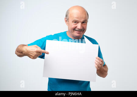Senior hispanic man with mustache holds the white sign in a studio white background Stock Photo