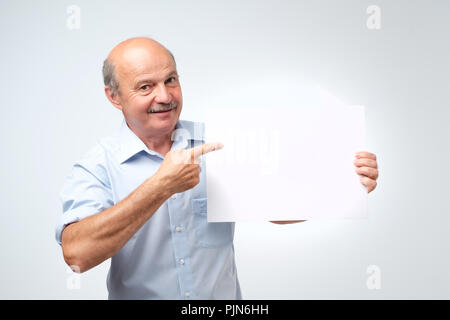 Senior hispanic man with mustache holds the white sign in a studio white background Stock Photo