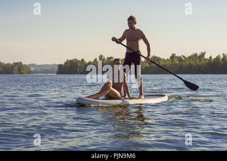 sports man and woman on vacation sport on stand up paddle board SUP newlyweds Stock Photo