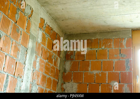 Detail of brick walls and concrete ceiling of a room in house under construction. Stock Photo