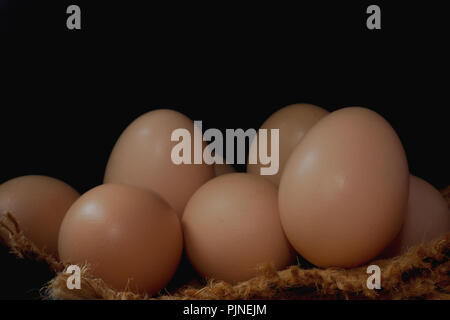 Eggs in a nest on hemp sack, dark corner. Stock Photo