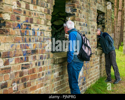 John Muir Country Park, Dunbar, East Lothian, Scotland, UK, 8th September 2018. Two older men look inside the open windows of an abandoned World War II brick building Stock Photo