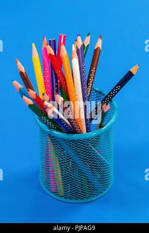 Colored pencils in a pencil case on blue background with copy space. Stock Photo