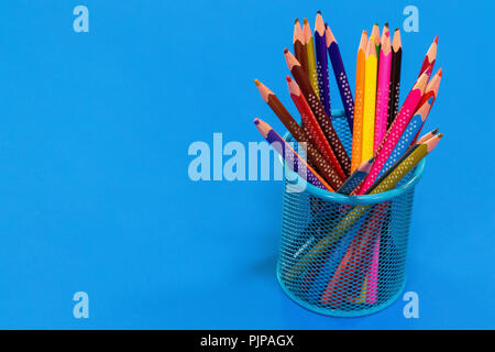 Colored pencils in a pencil case on blue background with copy space. Stock Photo