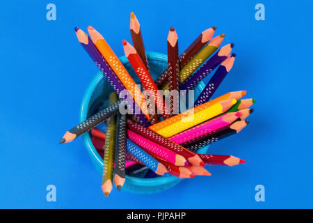 Colored pencils in a pencil case on blue background, top view. Stock Photo