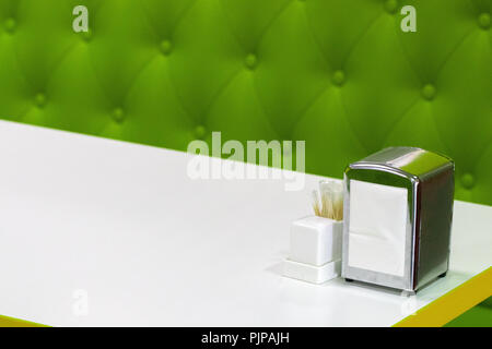 A restaurant or cafe table top set up on a white background with copy space, includes, a napkin holder, salt and pepper shakers. Food service concept. Stock Photo