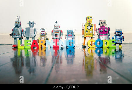 LEARNING CODE wooden letters and retro robot toys on a wooden floor with reflection Stock Photo