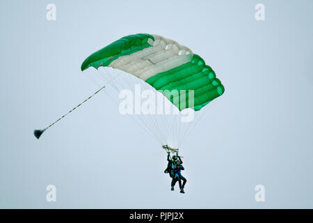 Skydivers under modern parachutes coming in to land on airfield. Stock Photo