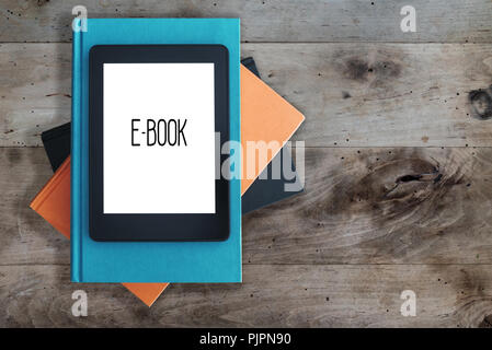 e-book reader on a stack of books on rustic wooden table concept Stock Photo