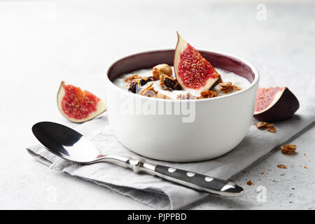 Healthy breakfast concept. Homemade yoghurt with organic granola, nuts and fig fruits in small bowl. Stock Photo