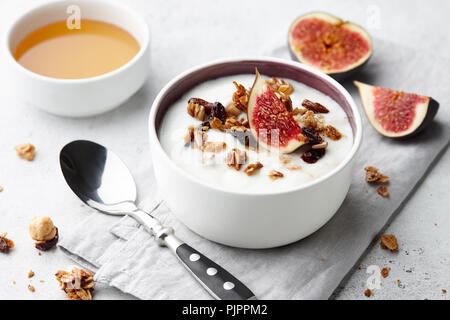 Healthy breakfast concept. Homemade yoghurt with organic granola, nuts and fig fruits in small bowl. Stock Photo