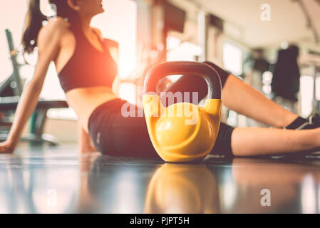 Close up kettlebells with woman exercise workout in gym fitness breaking relax after sport training center background. Healthy lifestyle bodybuilding  Stock Photo