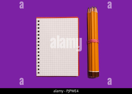 spiral opened notebook with pencils lying on a purple background. concept of office stationary. free copyspace Stock Photo
