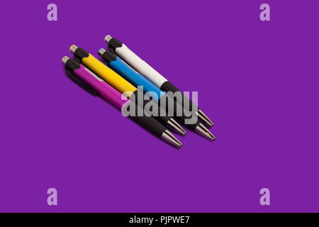four different new bright colored pens lying on a purple background. concept of office supplies. free copyspae Stock Photo