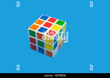 colorful plastic rubiks cube lying on a blue background isolated. concept of developing toys Stock Photo
