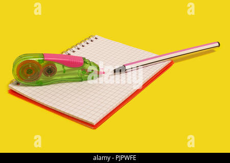 plastic green tape corrector and opened pen with stripes lying on a new notebook on a yellow background. concept of office and school chancery Stock Photo