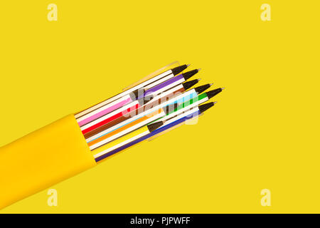 new bright colored pens lying in a box on a yellow background. view from the top. free space for advertising text. concept of office supplies Stock Photo